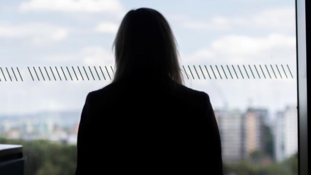 Lisa Scullion looking out of a window at the Manchester skyline