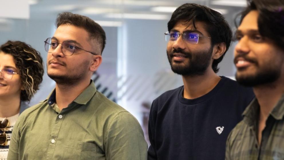 Four students stood in a row looking at something off camera