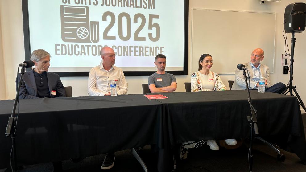 Five people sit at a table for a conference 