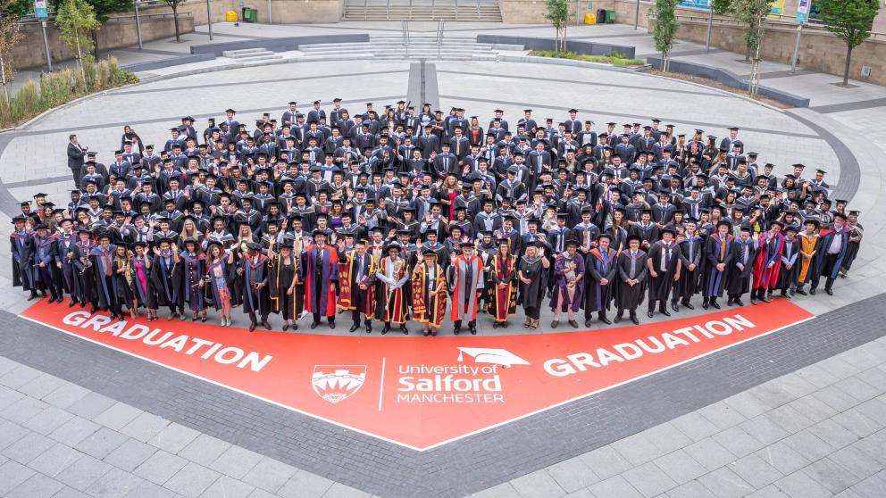 Graduates posing for a group photograph outside the The Lowry Building in Salford Quays