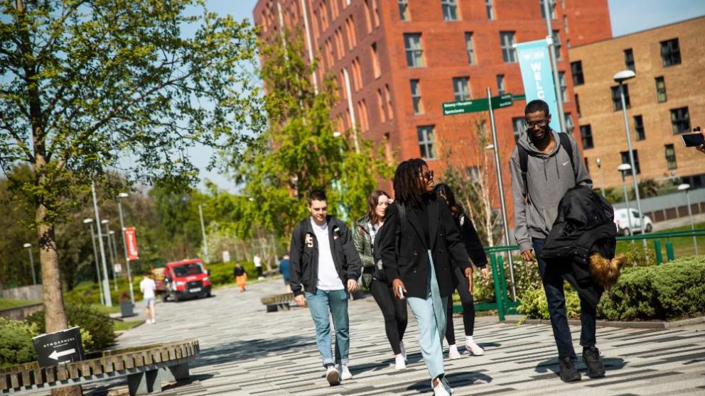 A group of students walking in front of Peel Park Quarter student accommodation