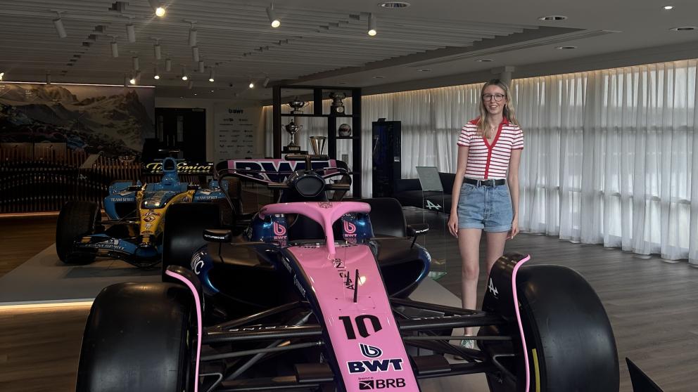 A woman stands next to a pink Formula One car