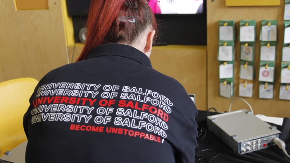 University staff member working at a laptop wearing 'Become Unstoppable' branded clothing