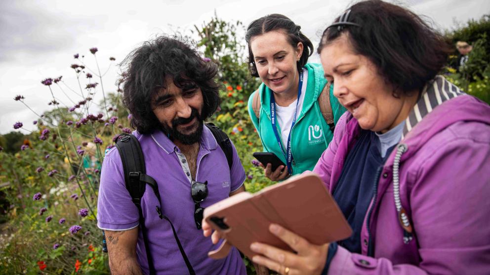 Three people looking at an iPhone camera in a garden 