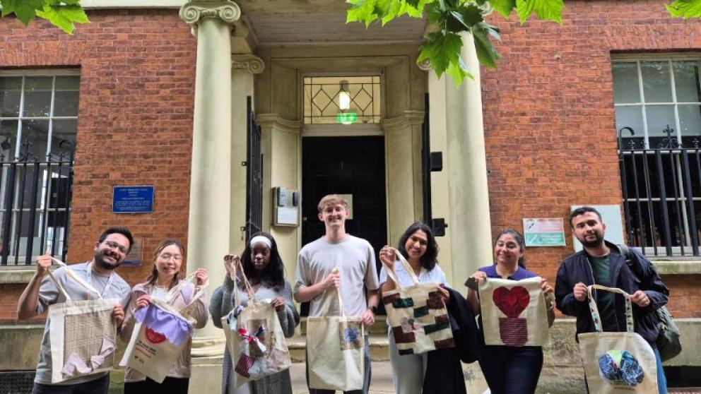A group of people smiling and holding their DIY tote bags after a tote bag workshop.