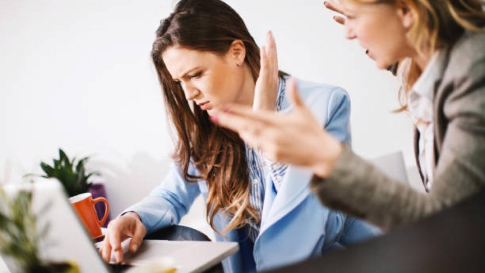 Two angry colleagues next to each other. Credit to iStock, powered by Getty Images.