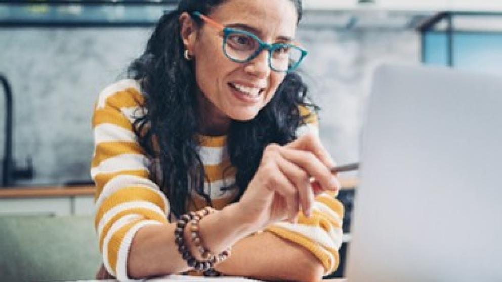 Female wearing glasses pointing at a laptop