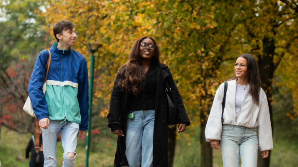 Three students walking through Peel Park Campus, University of Salford