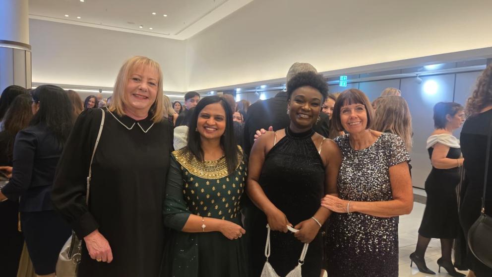 Four women are pictured at an awards ceremony, they smile at the camera