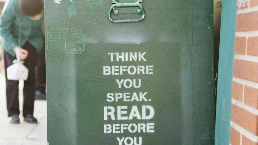 Image of graffiti on the side of a recycling bin that says "think before you speak. Read before you think."