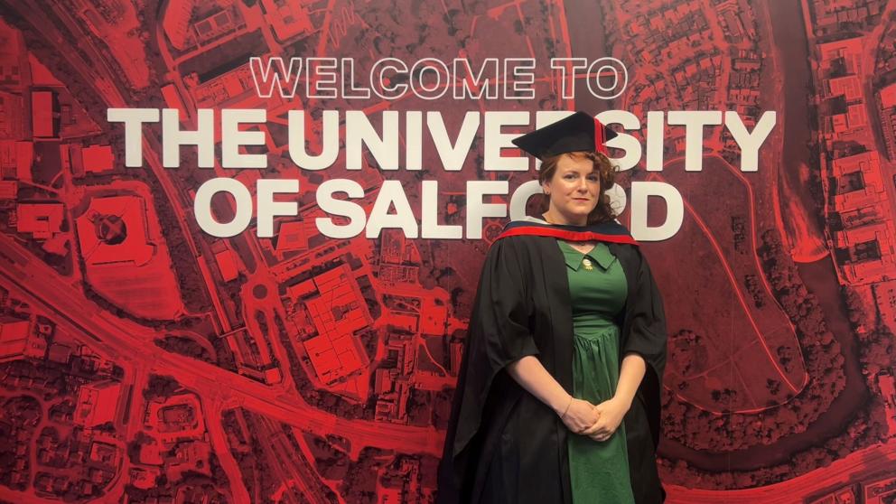 Nat Mulley is pictured in graduation cap and gown in front of a red background which says "The University of Salford"