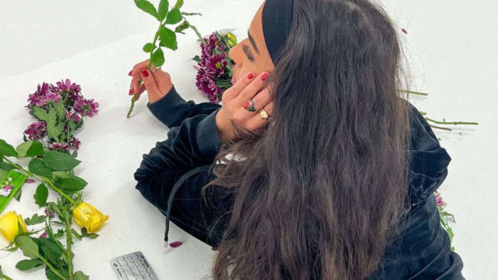 A young woman lies with head resting on hand while holding flowers