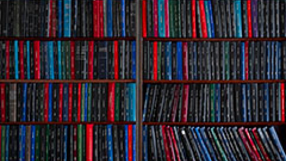 Shelves packed with rows of books arranged vertically, showing spines of various colors.