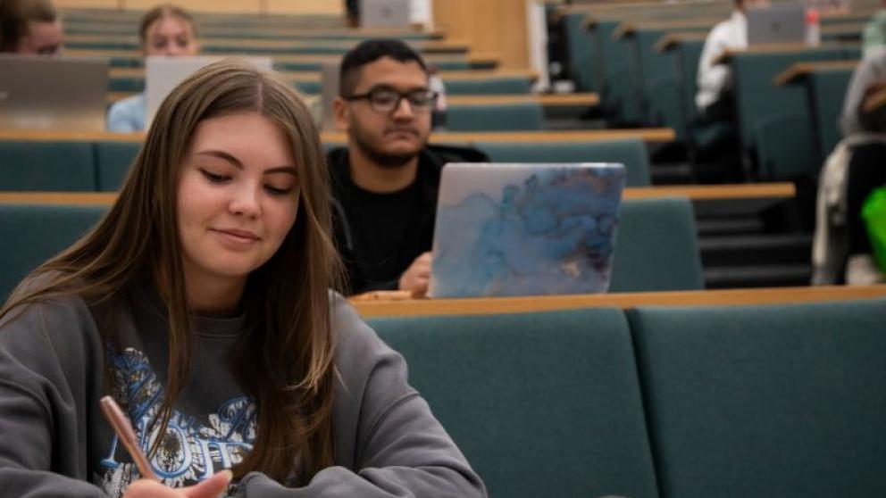 Students studying with laptops and notepads during a lecture