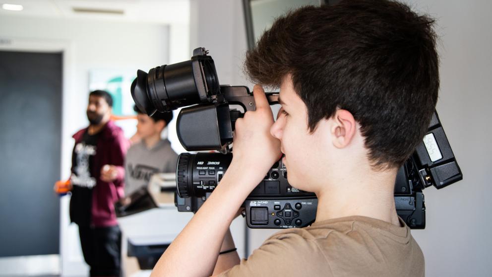 A young boy holds a video camera 