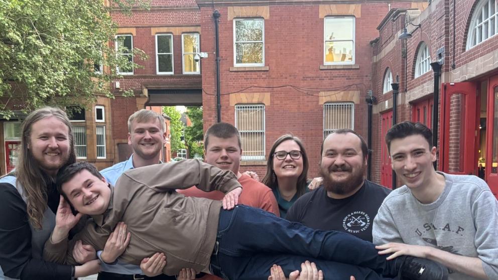 Group of people standing outside of red-brick building 