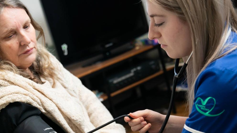 Nurse taking a patient's blood pressure in their home