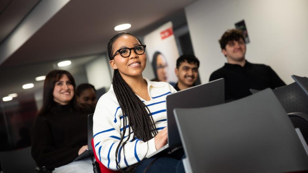 Students in a class, looking past the camera and smiling