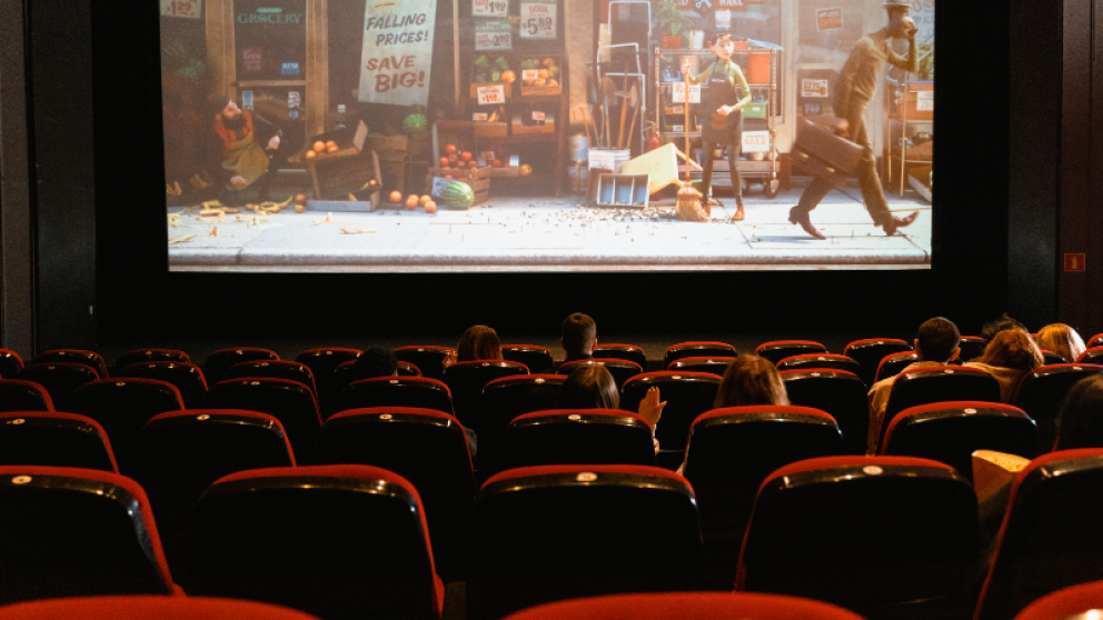 Rows of red cinema seats with an animated film showing on a screen