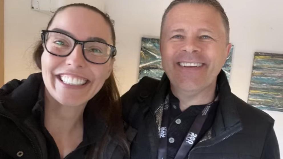 A head and shoulders selfie of a man and a woman smiling at the camera