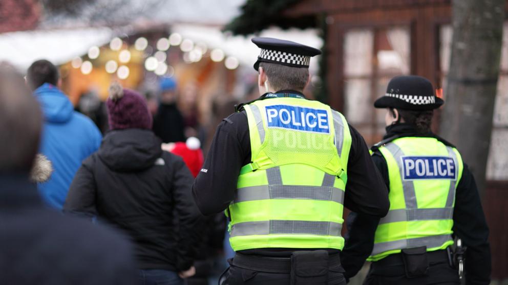 A male and female police officer walking with their backs to the camera