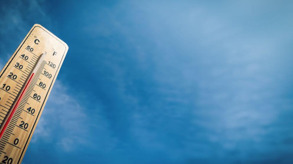 An upwards angle of a rising thermometer in front of a blue sky