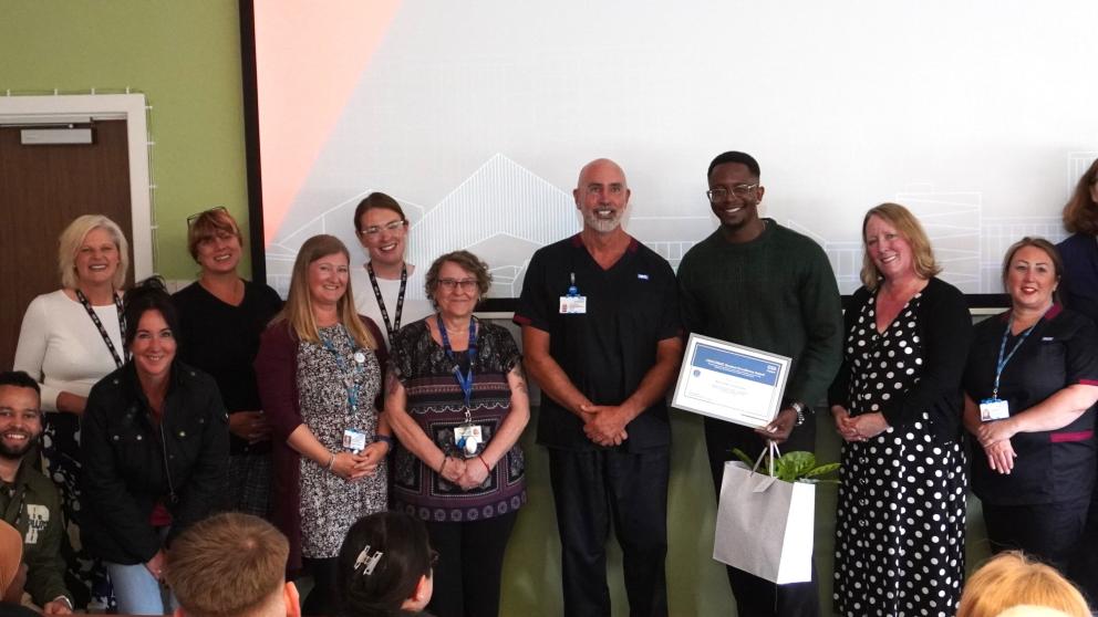 Ike receiving his award from University of Salford and Pennine Care teams