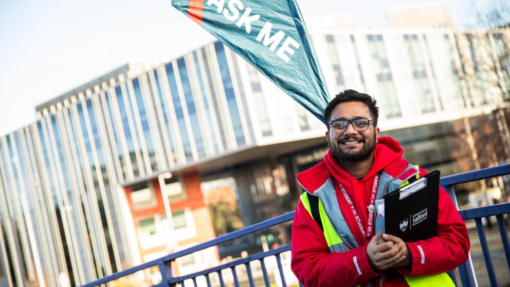 A student ambassador posing in front of the modern, landmark New Adelphi Building, University of Salford