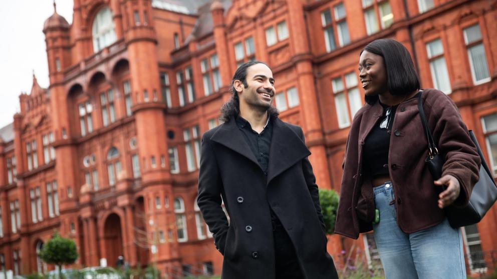 two students walking and smiling outside peel building