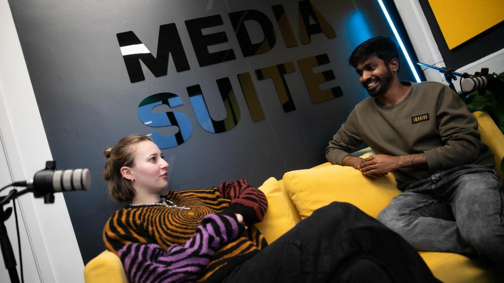 two students sat talking in media suite in salford business school