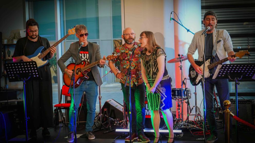 Band performing live on stage with guitars, drums and vocalists
