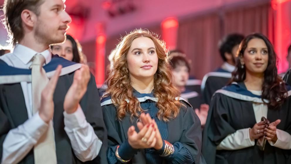 Graduates wearing traditional academic robes and hoods during a university graduation ceremony