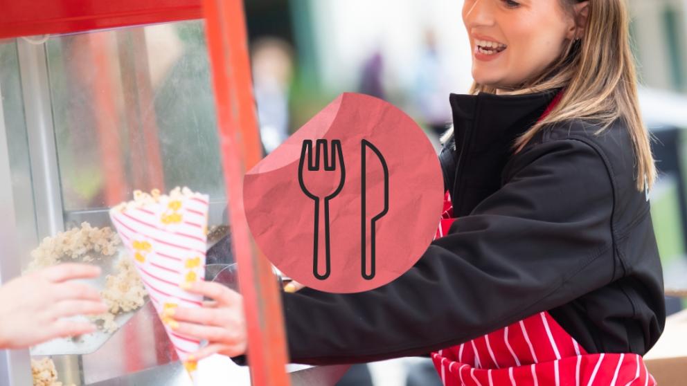 A staff member serving popcorn with a food and drink sticker