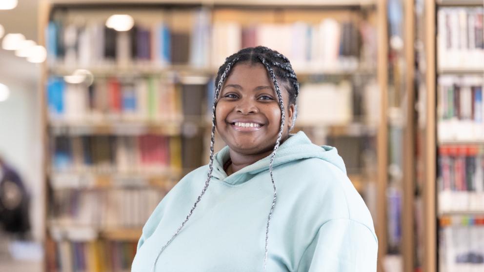 Colleague in a library setting stood in front of a bookshelf