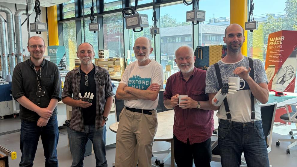 A group of men stood smiling at the camera, one of whom has a prosthetic arm
