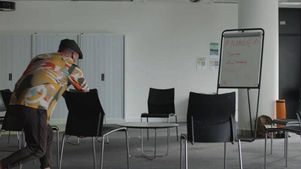 'Closed Off' video still showing a person arranging chairs in a meeting room