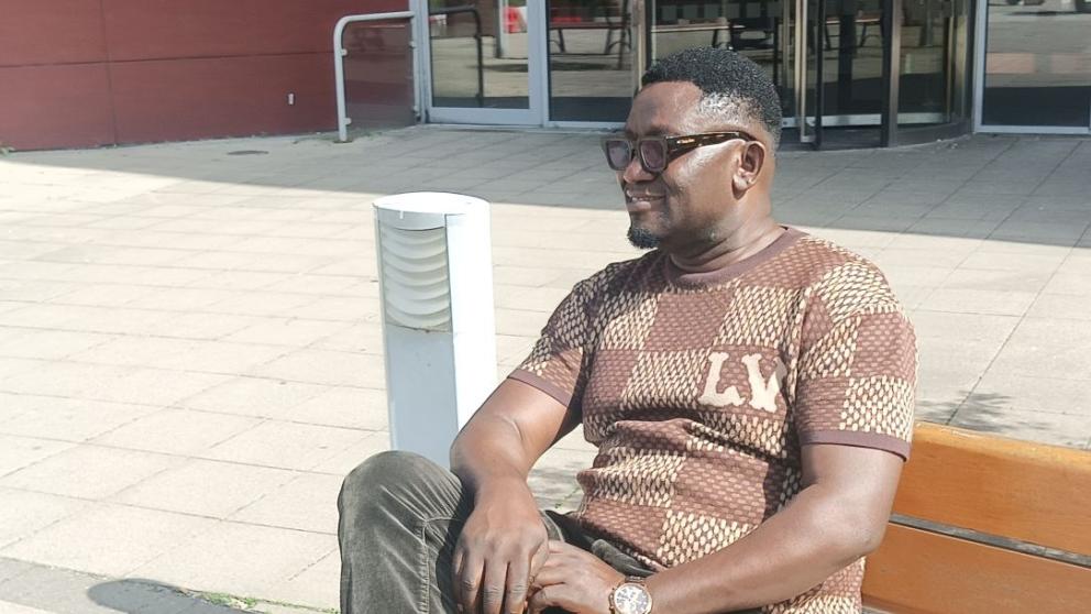 MSc Public Health international student Pedro, sitting outdoors on a wooden bench