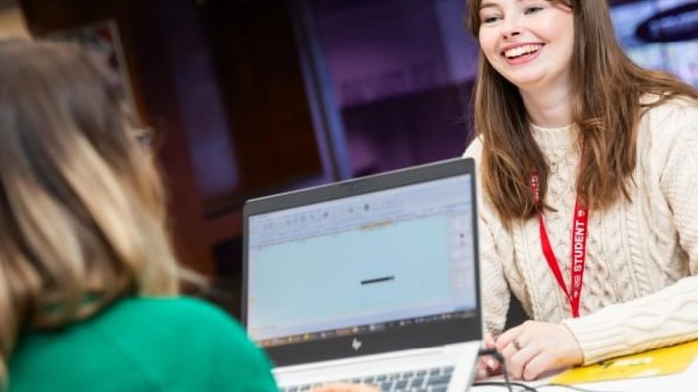 Student speaking to member of support staff behind a desk