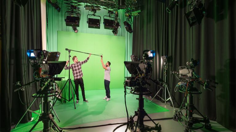 Two students setting up equipment in a green screen studio at MediaCity.