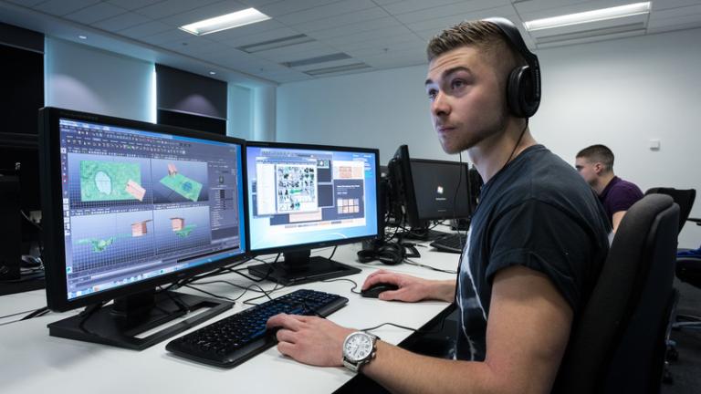 Student with multiple monitors working with gaming software