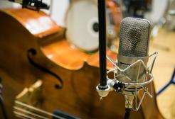 A microphone and a cello close up on a table in a music studio