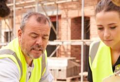 Group of surveying students wearing high-visibility jackets on a construction site
