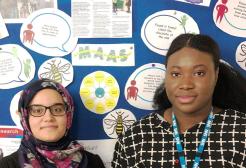 Two female biomedical science students, Suzan and Zoya standing in front of an educational bulletin board