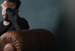 Seated person on a sofa holding their head in their hands