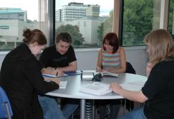 Four students gathered around a table reading and taking notes