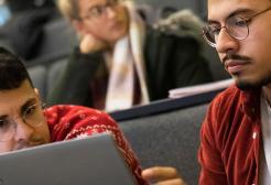 Students collaborating on a laptop in a lecture theatre