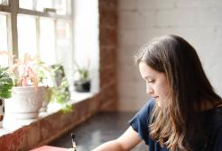Woman sat at a desk writing in a notebook