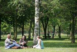 Three students sat in Peel Park, Salford