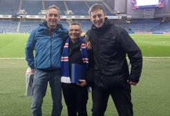 Three people stood together on a football field