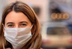 An individual wearing a light blue disposable face mask
